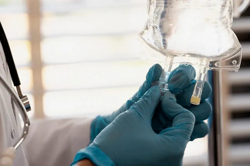 a person in a white coat and blue gloves is holding a sys CagriSema in their hand and a light bulb is in the background