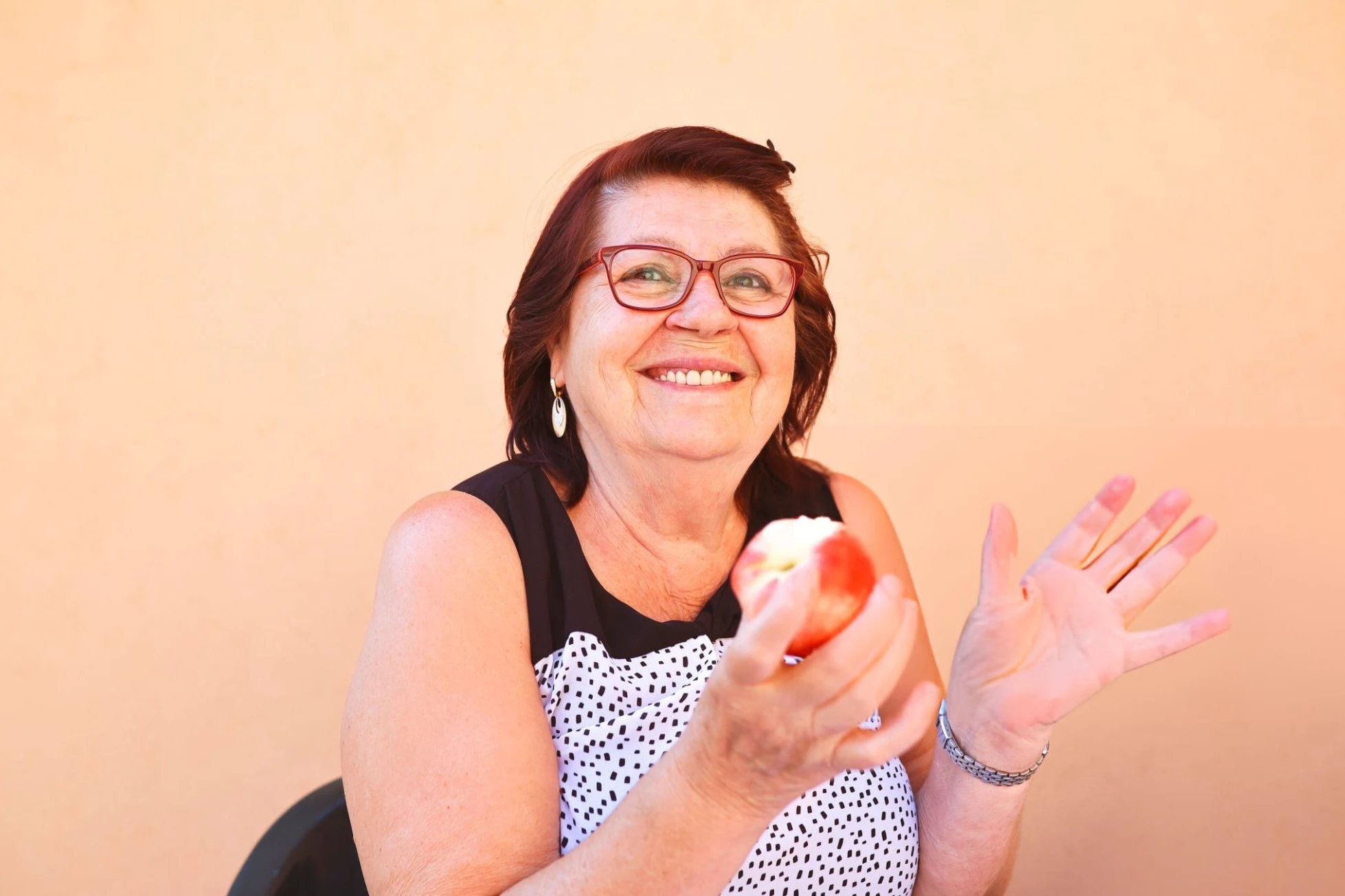 Portrait of a female senior eating a peach for her healthy breakfast